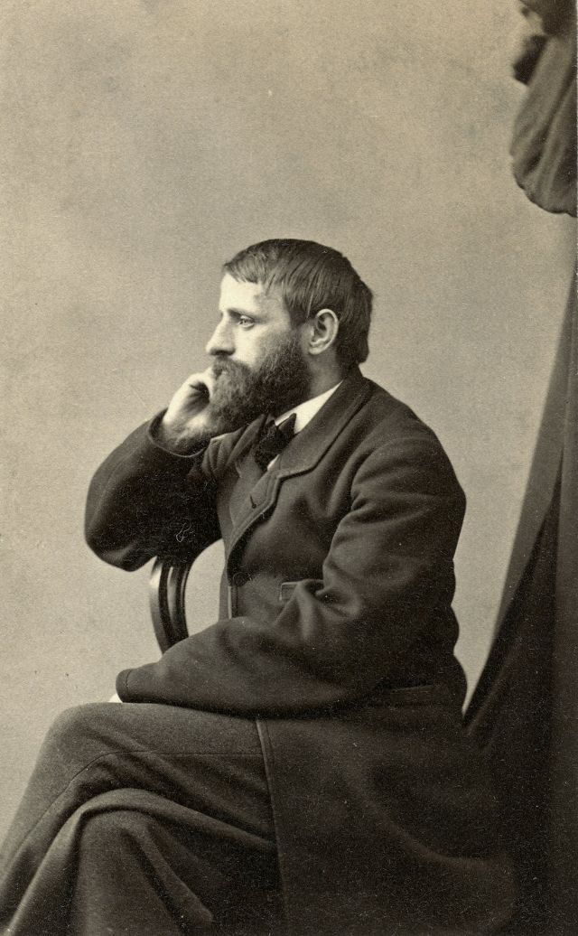 #4 A gentleman sits sideways on a chair, gazing off camera with hand to cheek in what appears to be a contemplative, thoughtful frame of mind
