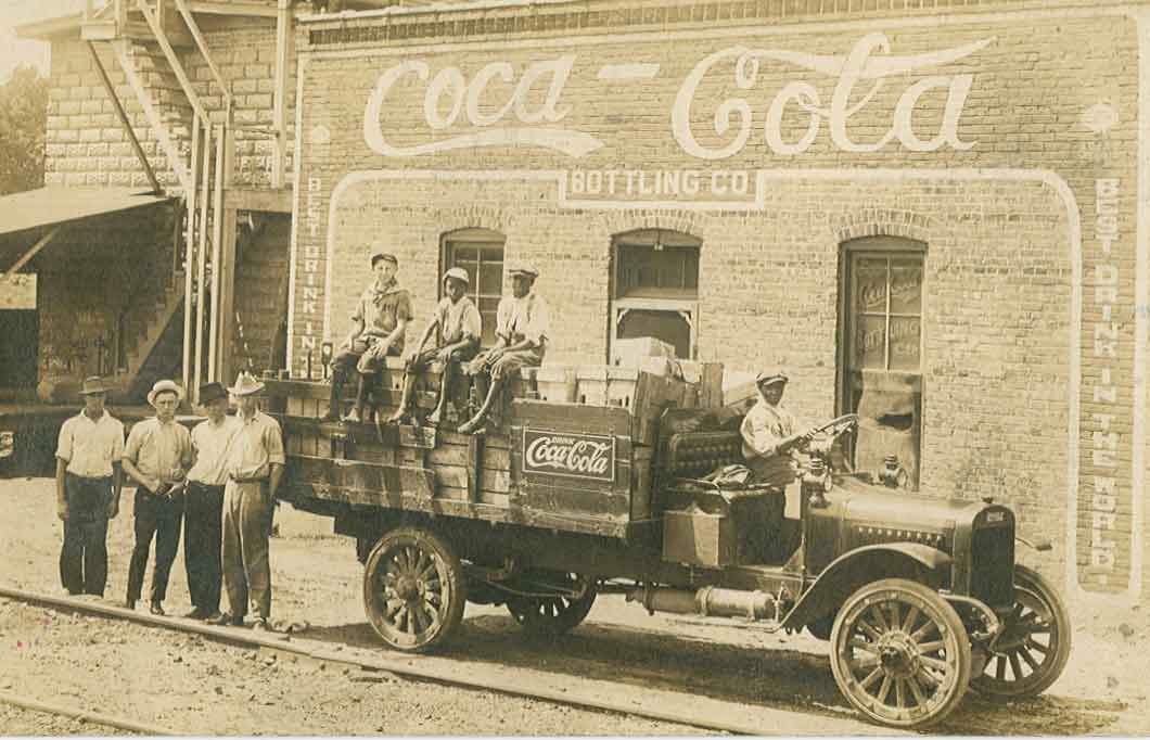 #25 A Coca-Cola delivery truck with three young boys seated on its side, 1900.