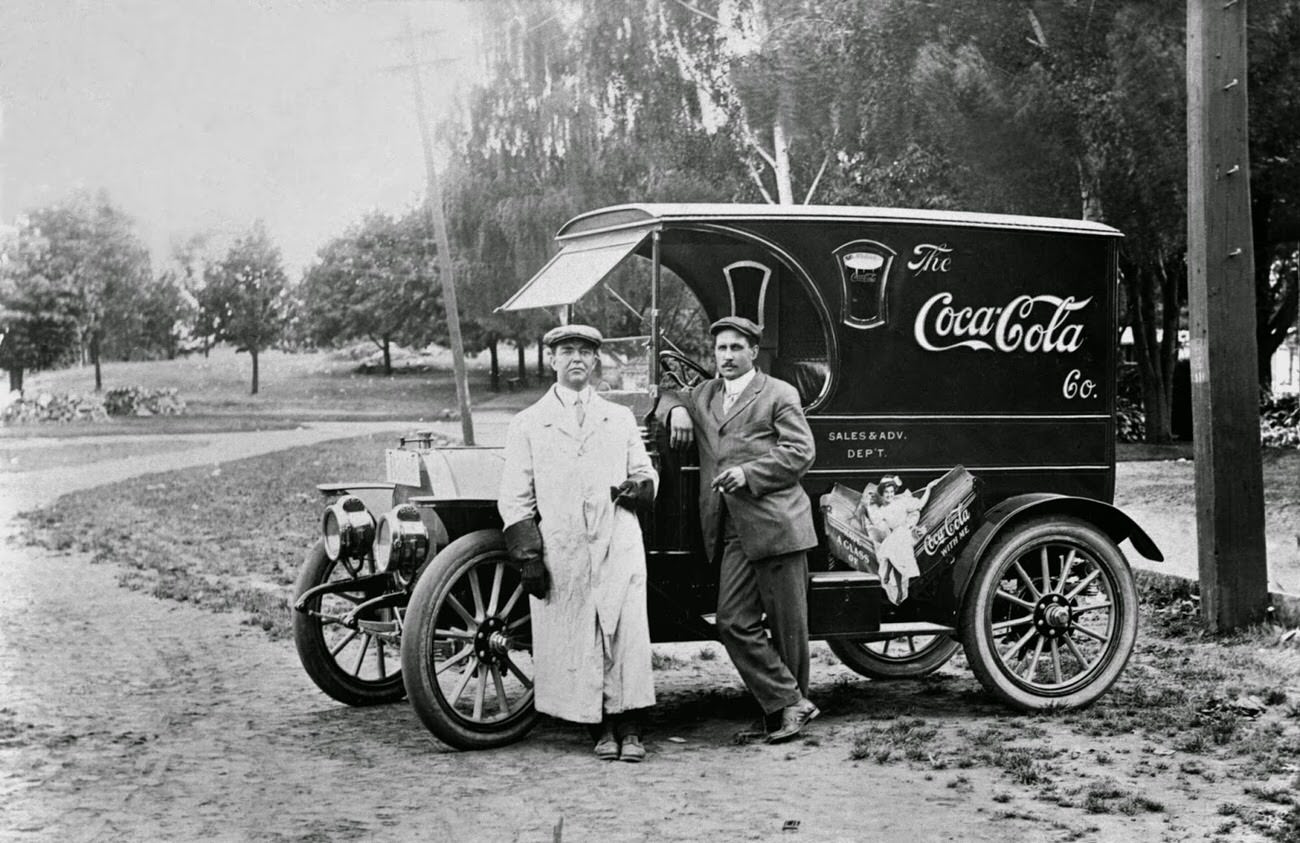 #13 Two men standing by a Coca-Cola delivery truck, 1910.