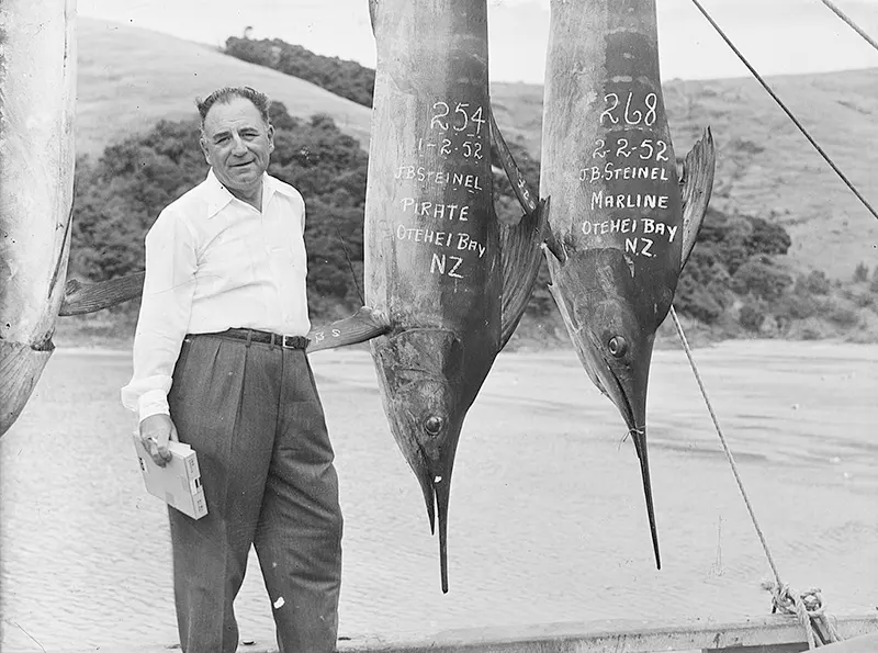 #16 Man with two large suspended fish, 1952.