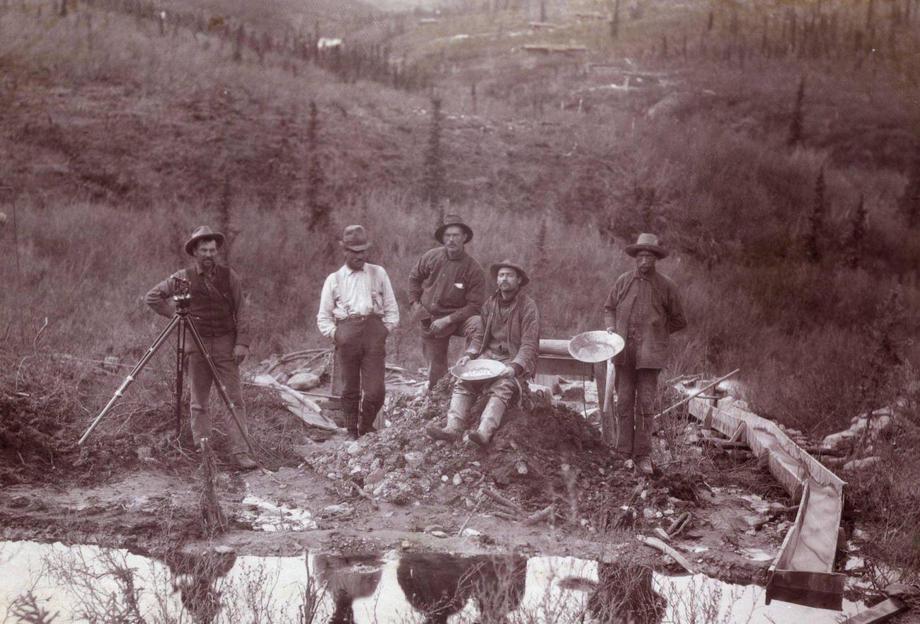 #10 Men beside a stream with gold panning tools in Little Dominion during the Gold Rush.