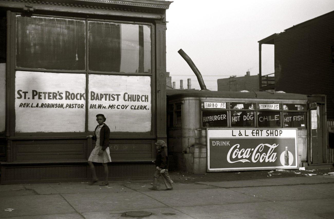 #39 African American outside a storefront church and lunch wagon in the Black Belt, Chicago, Illinois, circa 1941.