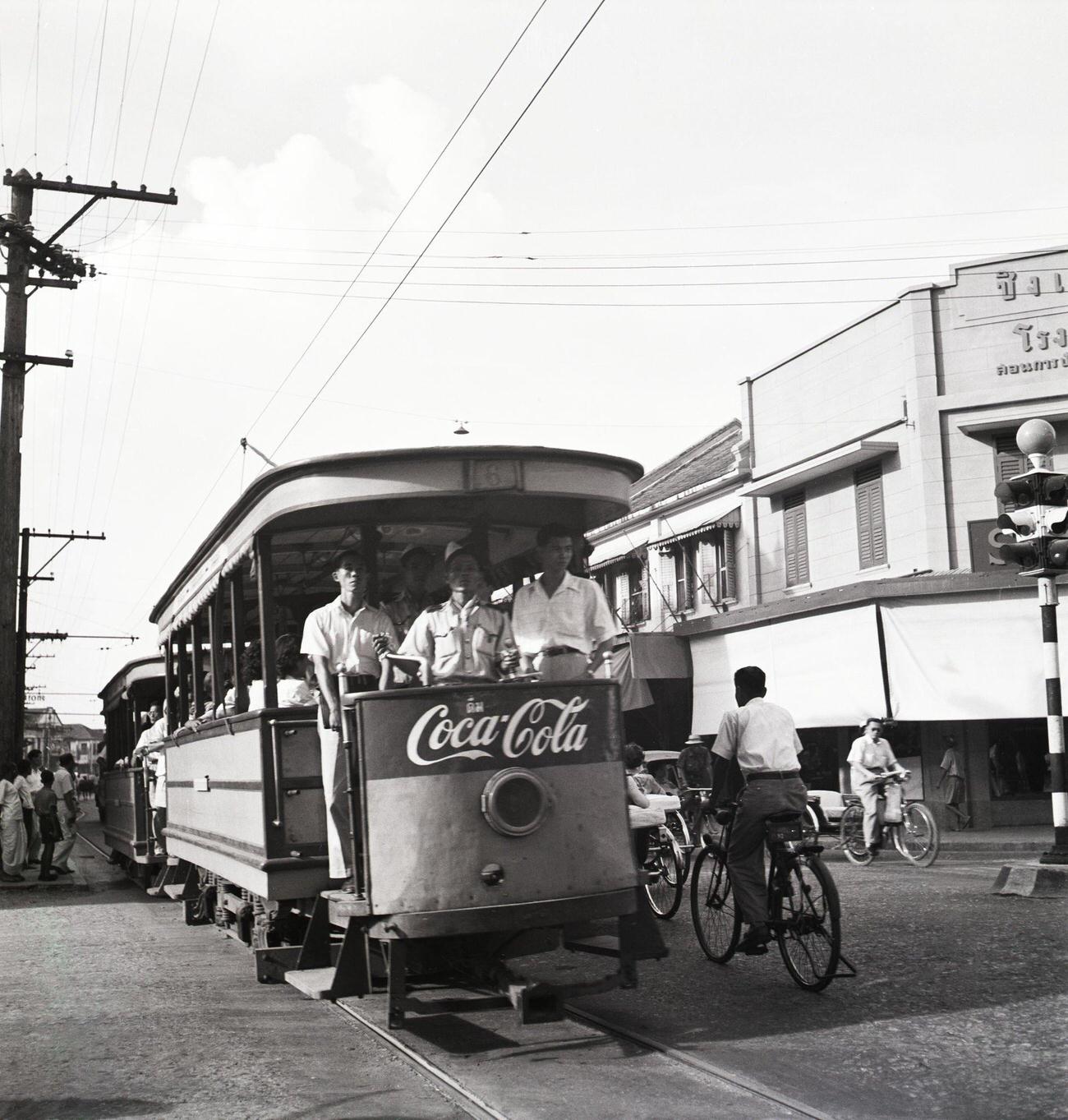 #66 Cyclists pedaling by trolleys advertising an American soft drink in Siam, May 26, 1950.