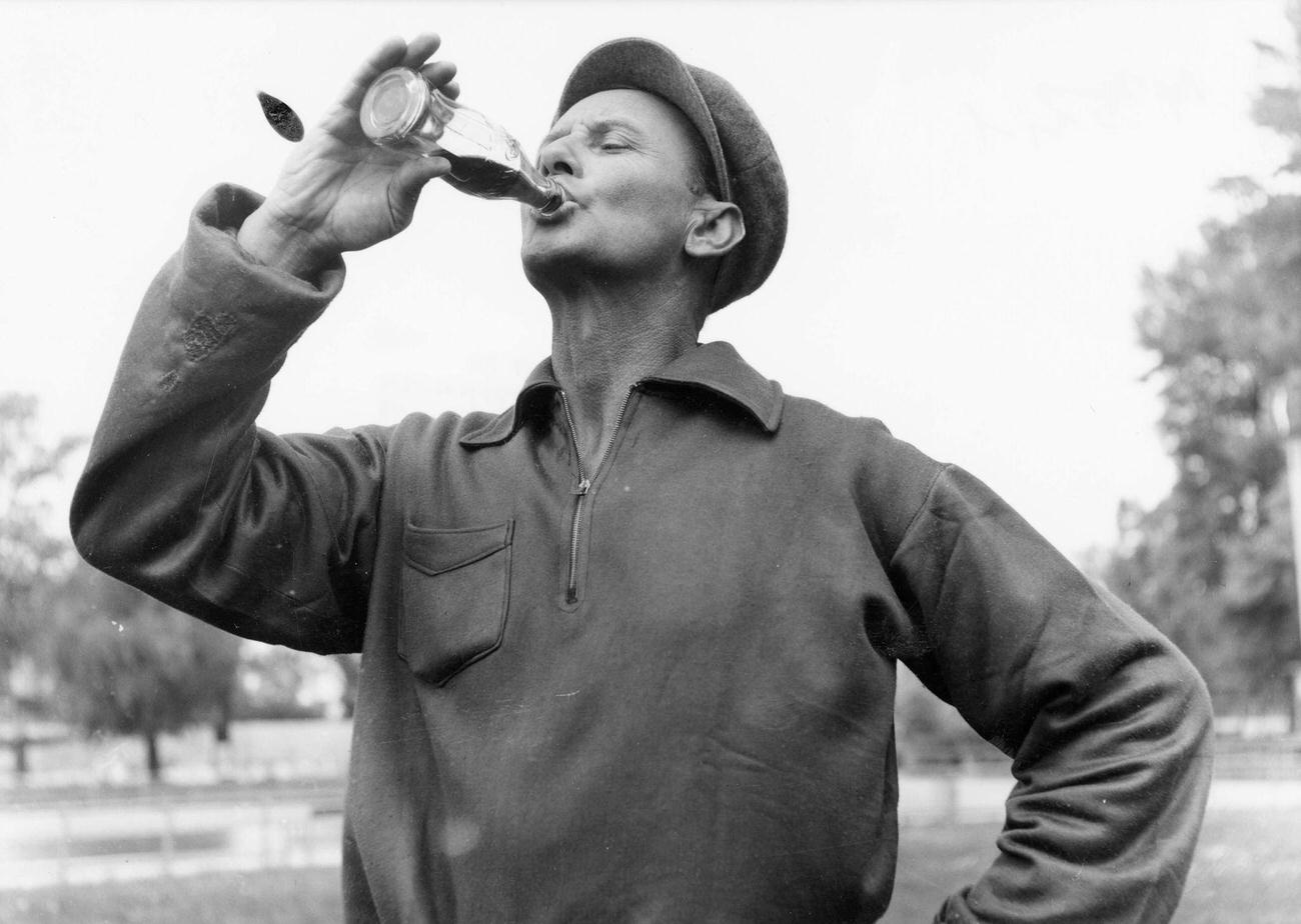 #82 A man drinking from a Coca-Cola bottle, 1955.