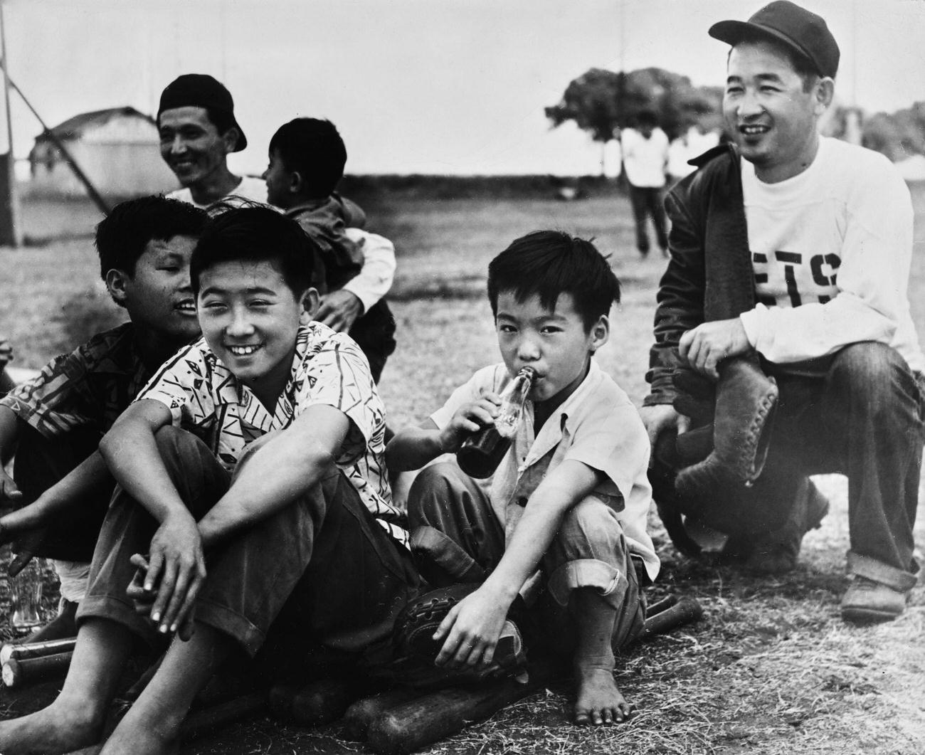 #83 Young Hawaiians, one drinking Coca-Cola, waiting to bat during a baseball game in Hawaii, circa 1955.
