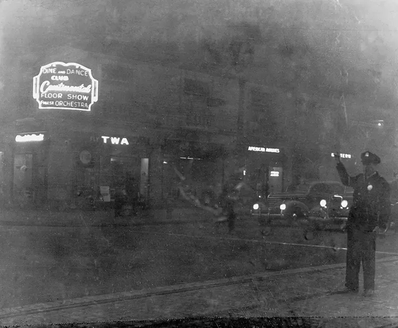 #19 Saint Louis street before smoke ordinance, featuring various signs and a traffic-directing officer.
