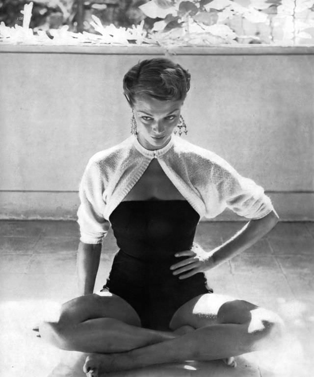 #19 Jean Patchett in a strapless navy-blue wool suit with back buttons and a brief white wool sweater by Tina Leser, in Jamaica, 1949.