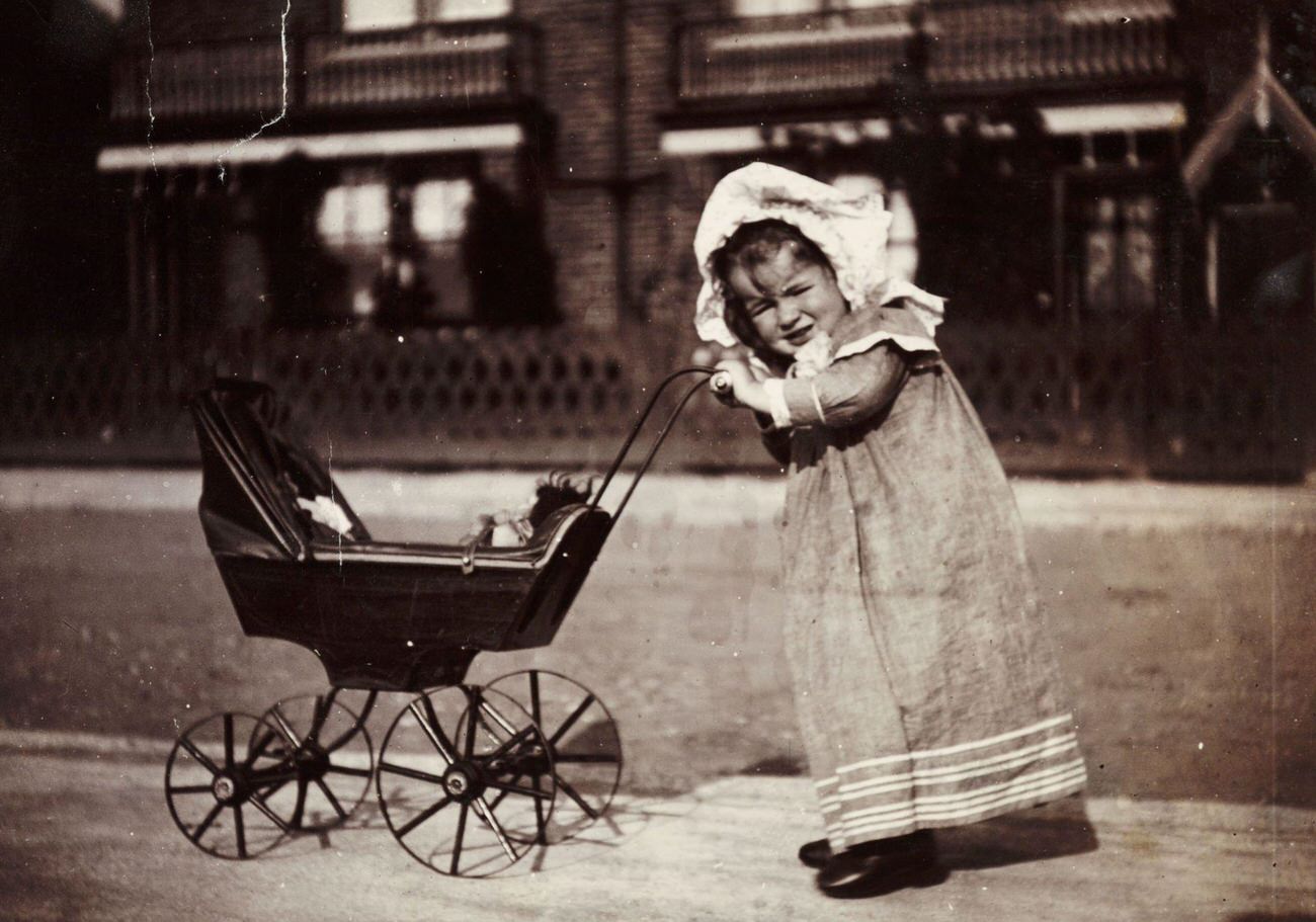 #41 Child pushing a toy pram, circa 1895.