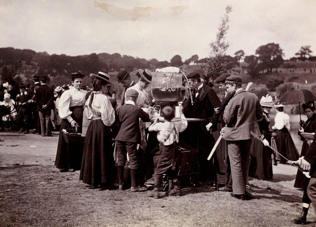 #49 People around a drinks fountain at a fairground, circa 1898.