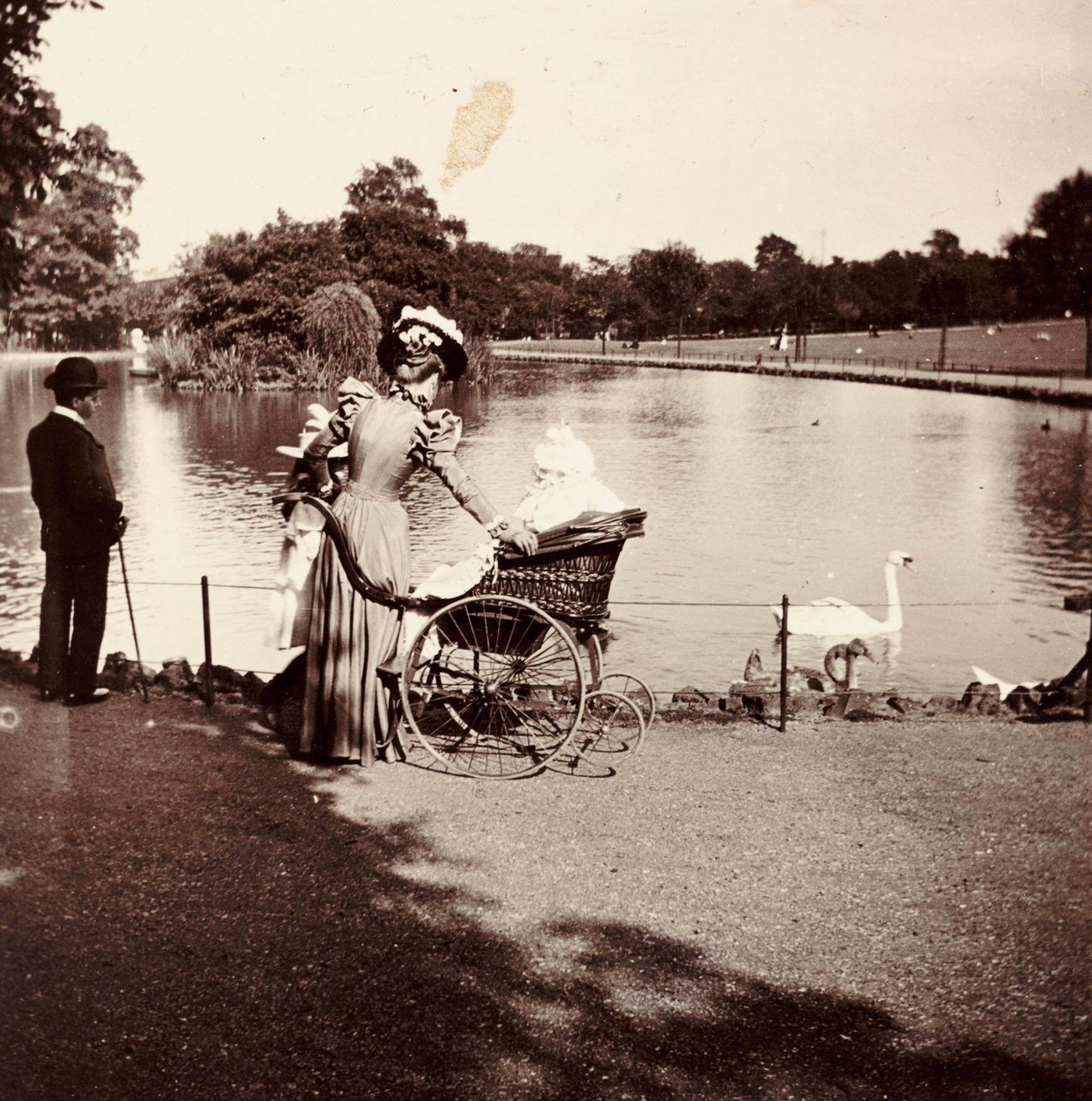 #58 Woman and wheelchair near a lake in a park, circa 1900.