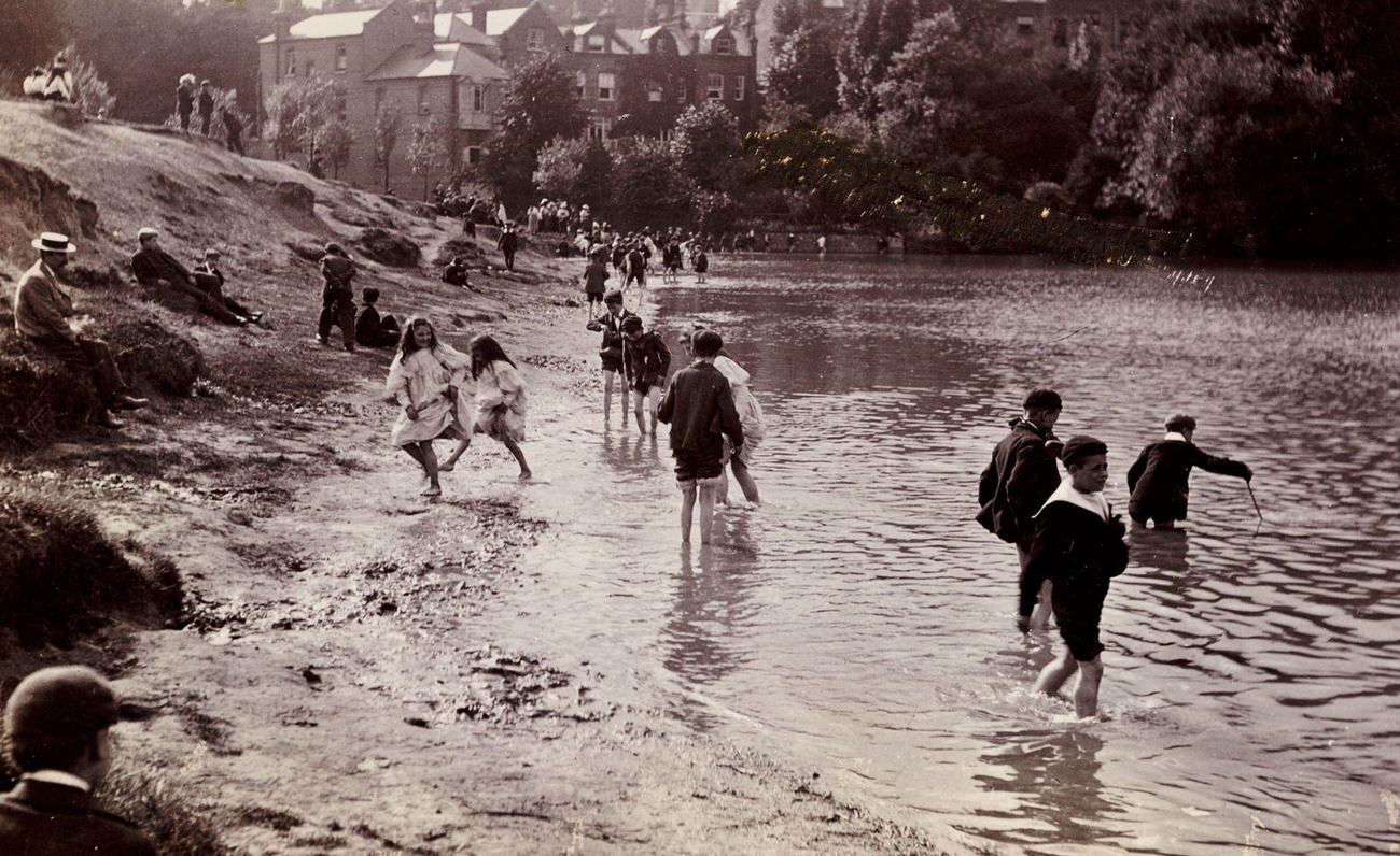 #61 Children playing in a river on a summer day, circa 1900.