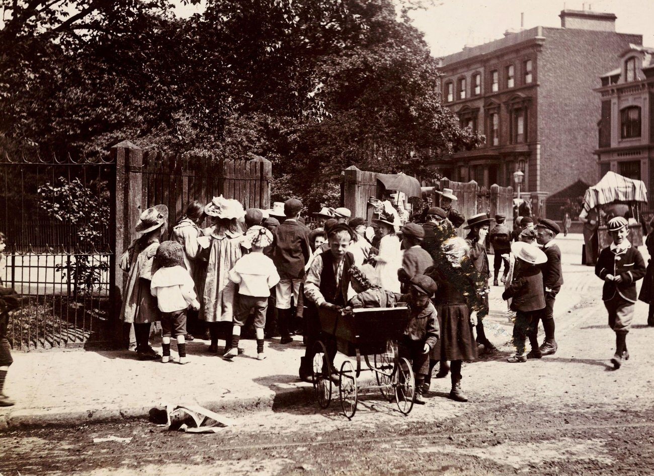 #62 Children gathering near a park entrance, circa 1900.