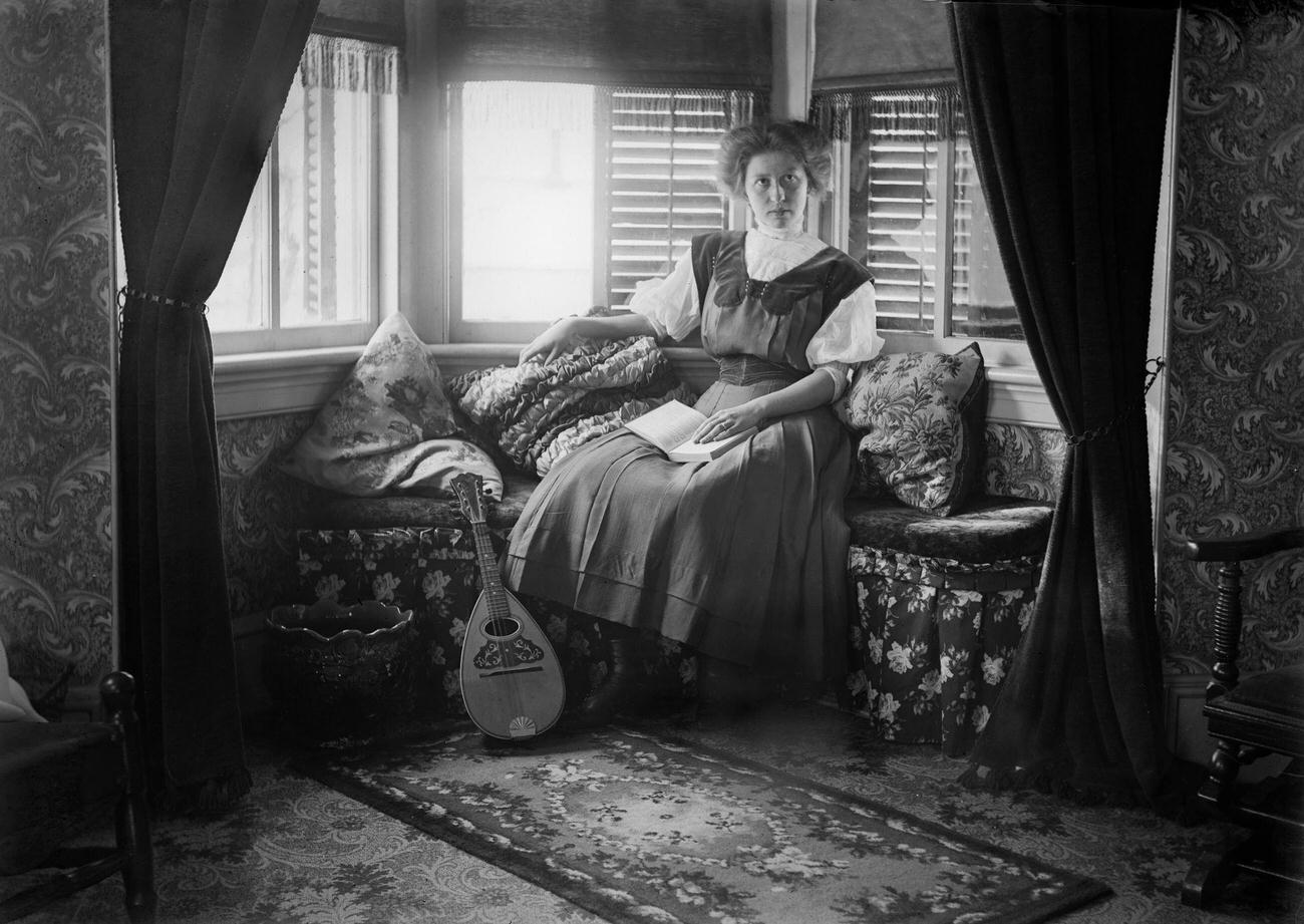 #71 A woman sitting in a Victorian-era parlor, circa 1900.
