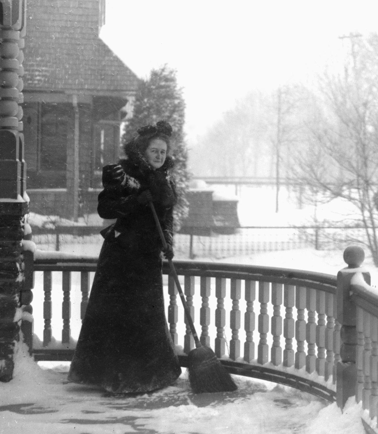 #73 Victorian woman clearing snow off her porch, circa 1900.