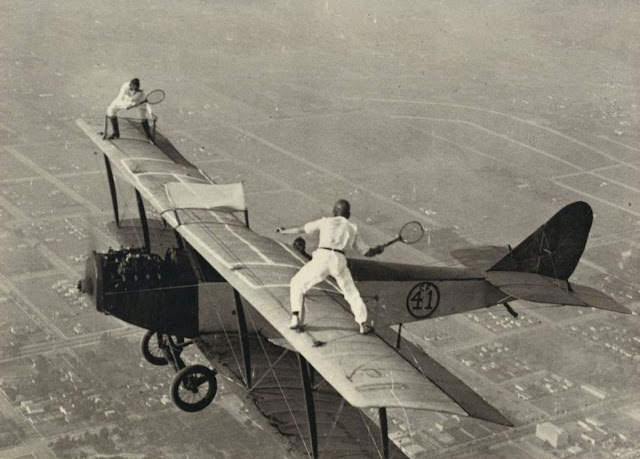 #11 Black Catters Ivan “Bugs” Unger and Gladys Roy enjoy a game of tennis on the upper wing of a Curtiss Jenny.