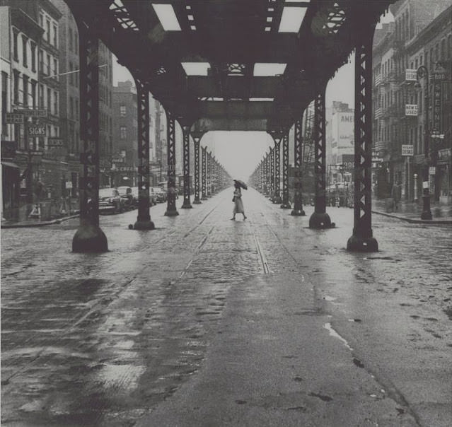 #6 Woman with umbrella walking across New York City street, January 1956
