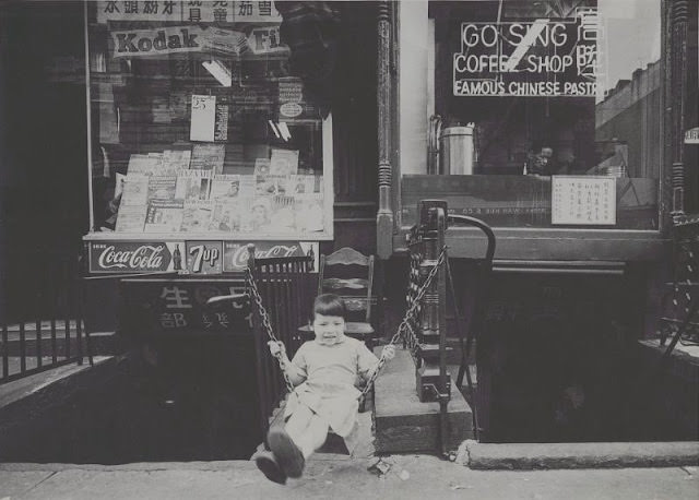 #28 Young girl swinging outside of Go Sing Coffee Shop, September 1958