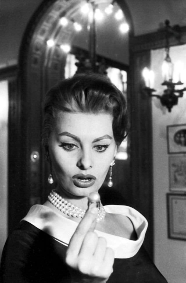 #16 Sophia Loren admiring a pearl ring at Cartier in Paris, given a bronze Eiffel tower, 1956.