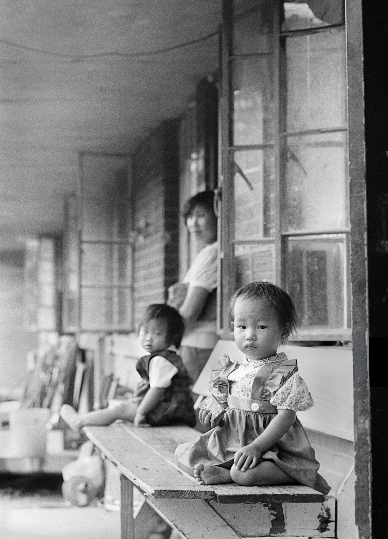 #51 An Asian immigrant mother with her two daughters on their front porch, Houston, Texas, 1983.