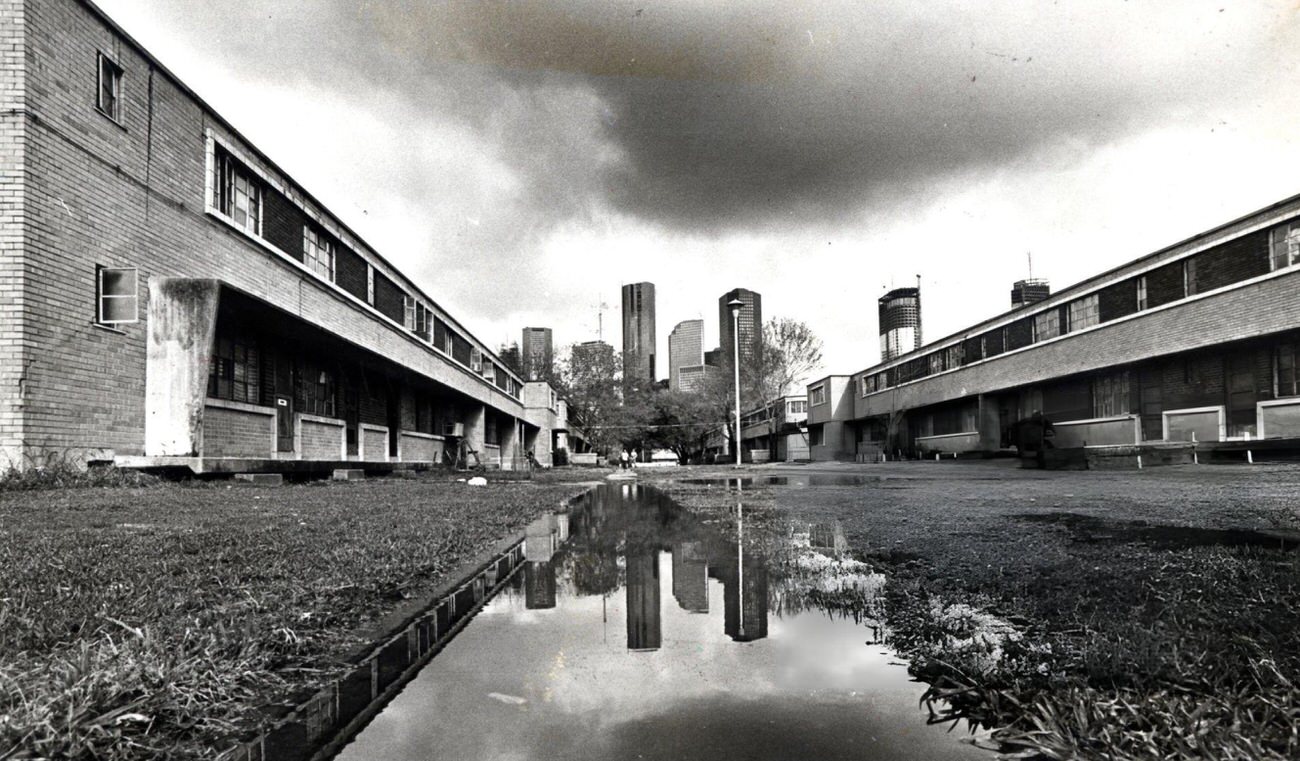 #53 Houston skyline reflected in a puddle at Allen Parkway Village, Houston, Texas, 1983.
