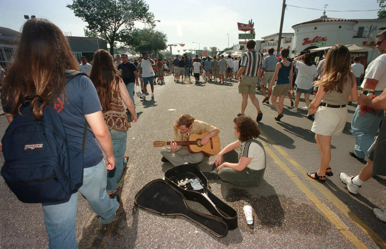 #57 Patrick Napier and Melissa Garrett play guitar amid the crowd at the Westheimer Street Festival, Houston, Texas, 1998.