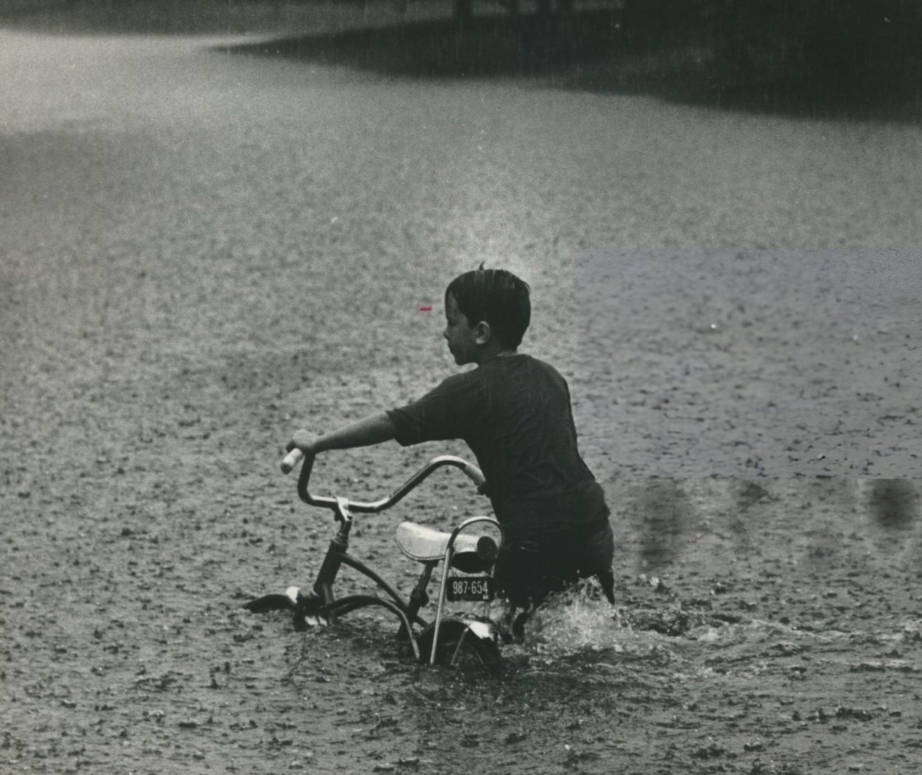 #33 A boy navigates floodwaters on his bicycle in Houston, Texas, 1970.