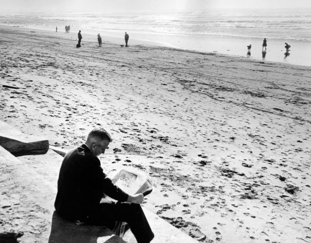 #133 Man reading a newspaper at Ocean Beach, 1960.