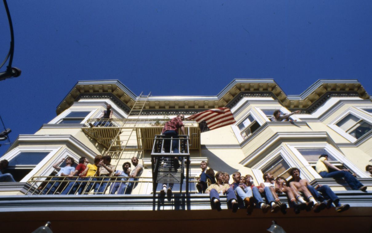#95 People sitting on fire escapes and a building ledge, 1977.