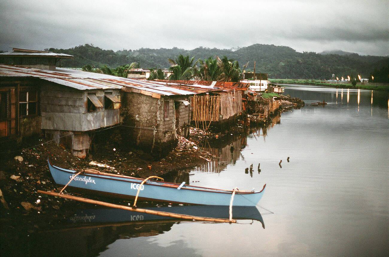 #40 Poverty-stricken houses along a riverbank at sunset, 1981.