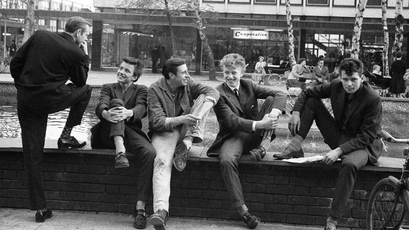 #21 The boys of Stevenage in Hertfordshire beating their nightly battle with boredom in the town square, October 1959.
