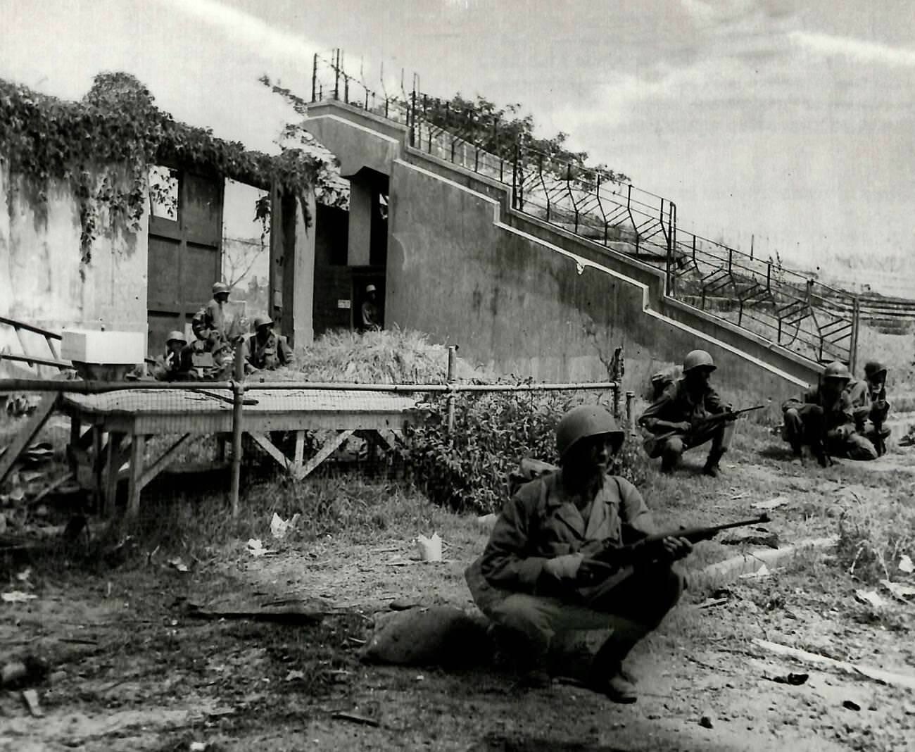 #36 American machine gunners and riflemen defend against Japanese forces from positions at a Manila stadium’s back wall, Philippines, 1945.