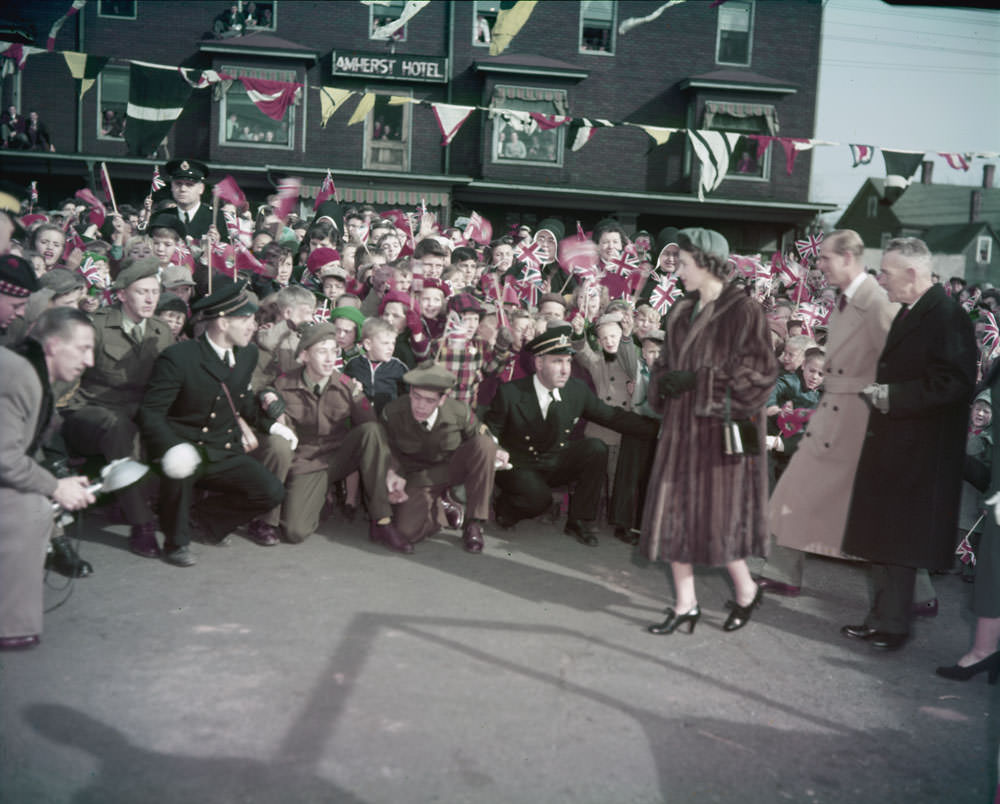 #15 Queen Elizabeth II, Prince Phillip and another elderly man stand before a crowd of spectators, 1951