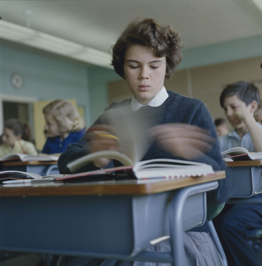 #17 Girl sitting at desk flipping through textbook pages at Putnam School