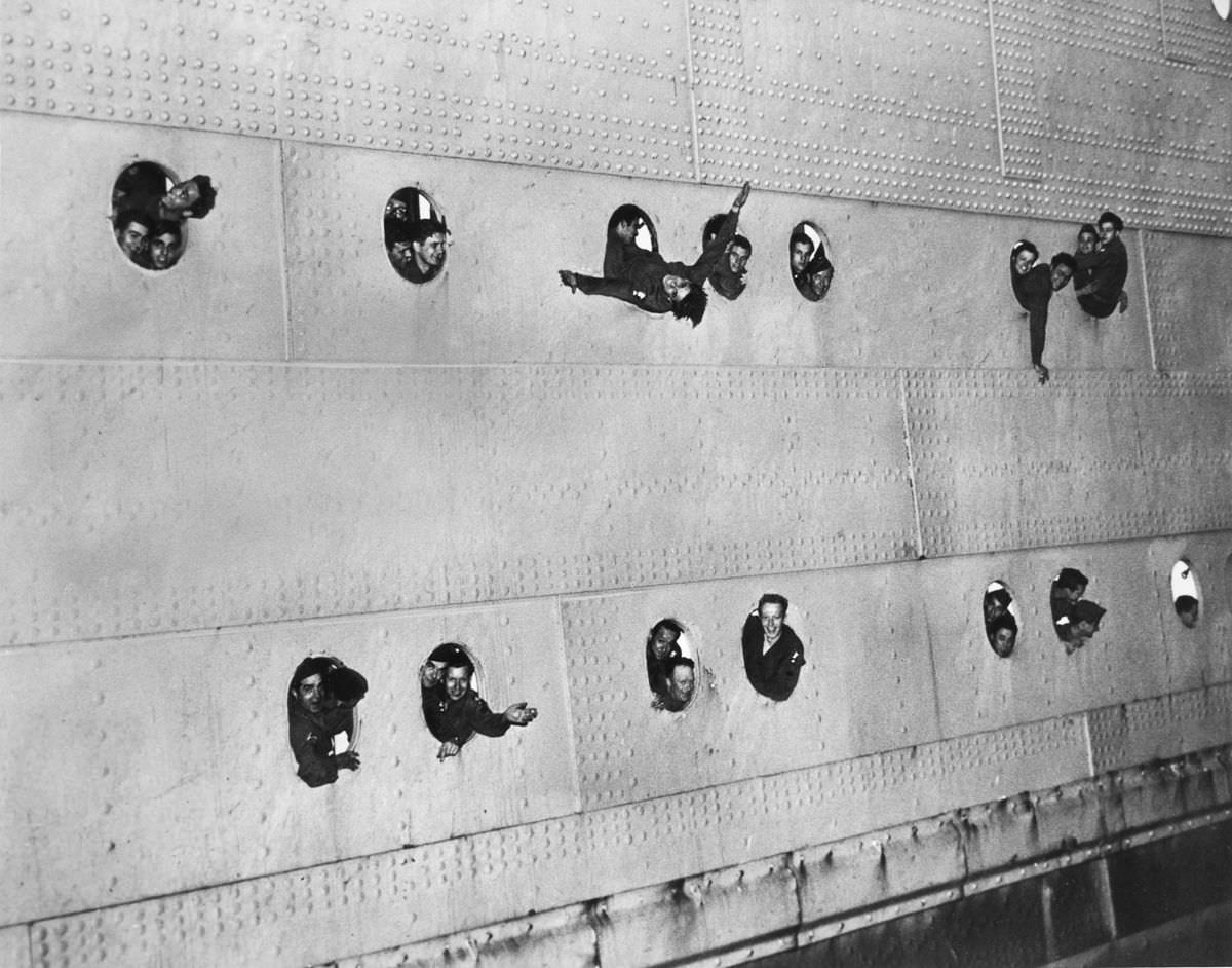 #9 Military personnel wave from the portholes of a ship, 1945.