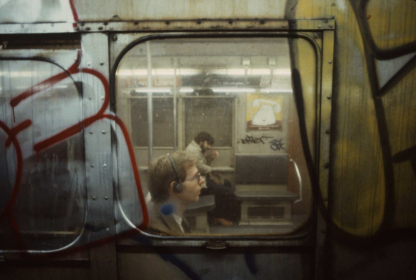 #11 A man is seen wearing headphones through a subway car window, 1981.