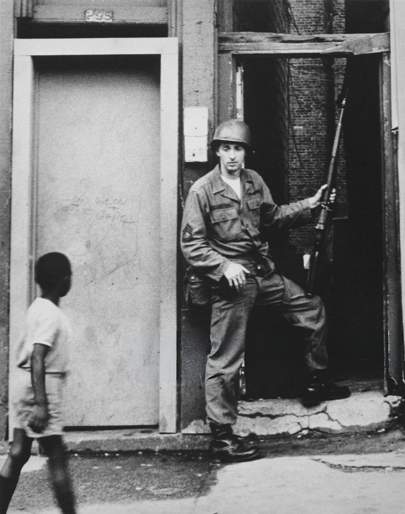 #18 A young African American boy passes a National Guardsman in an alley of Springfield Avenue