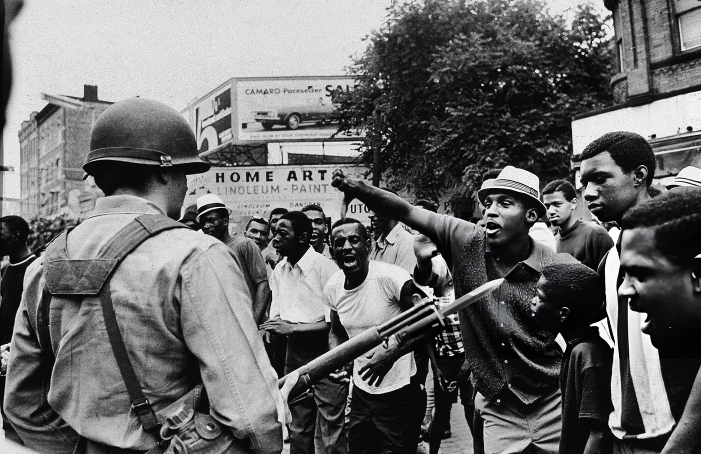 #7 A Black man gestures with his thumb down to an armed National Guardman, during a protest