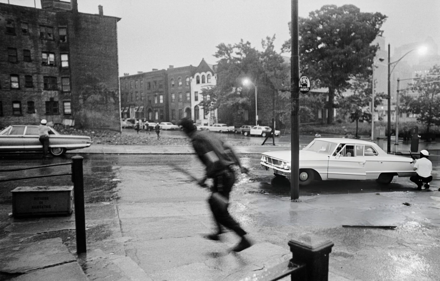 #25 Police take cover behind parked cars during the riots in Newark, New Jersey, 1960s.