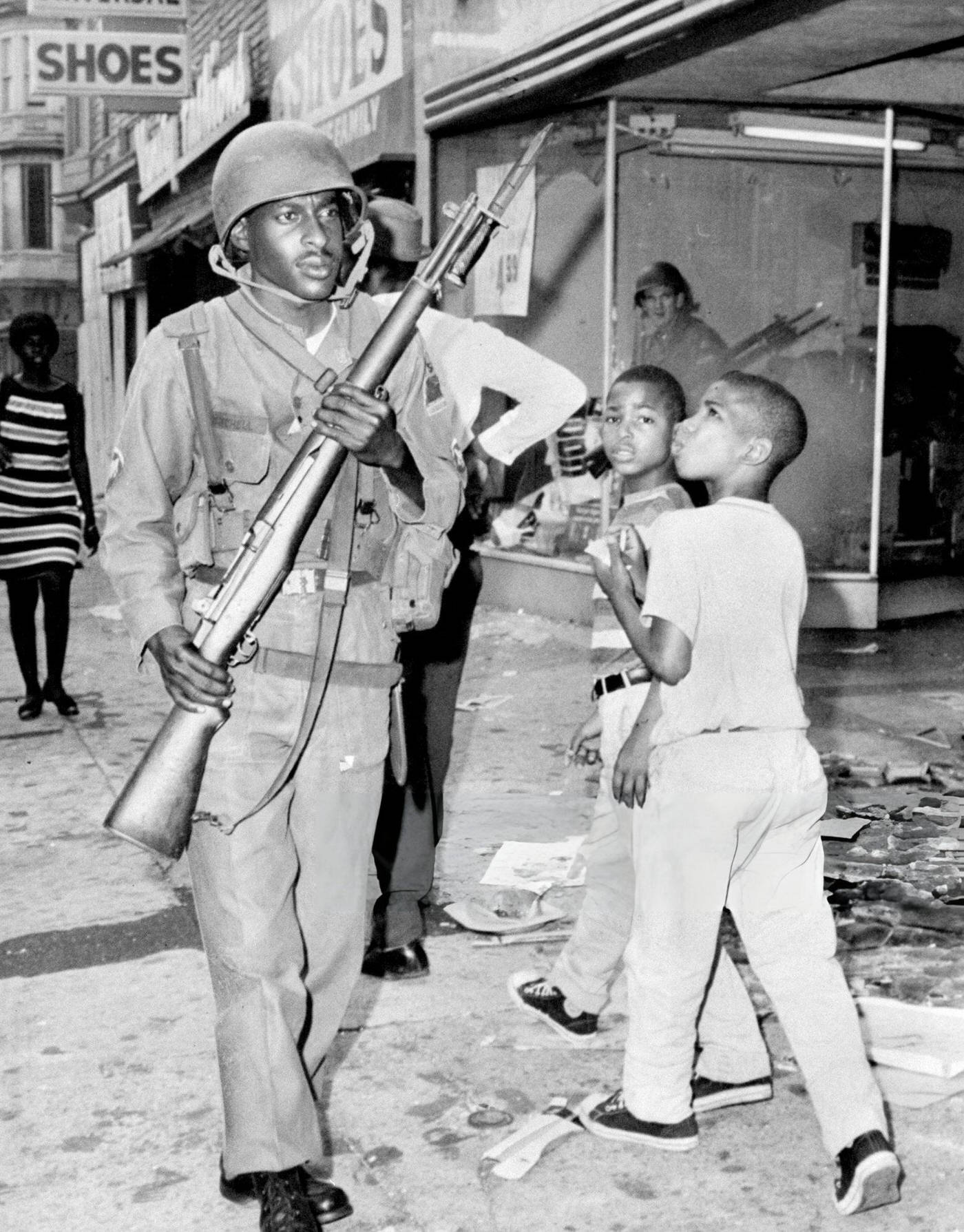 #29 Newark children pass National Guardsman during riots, 1960s.