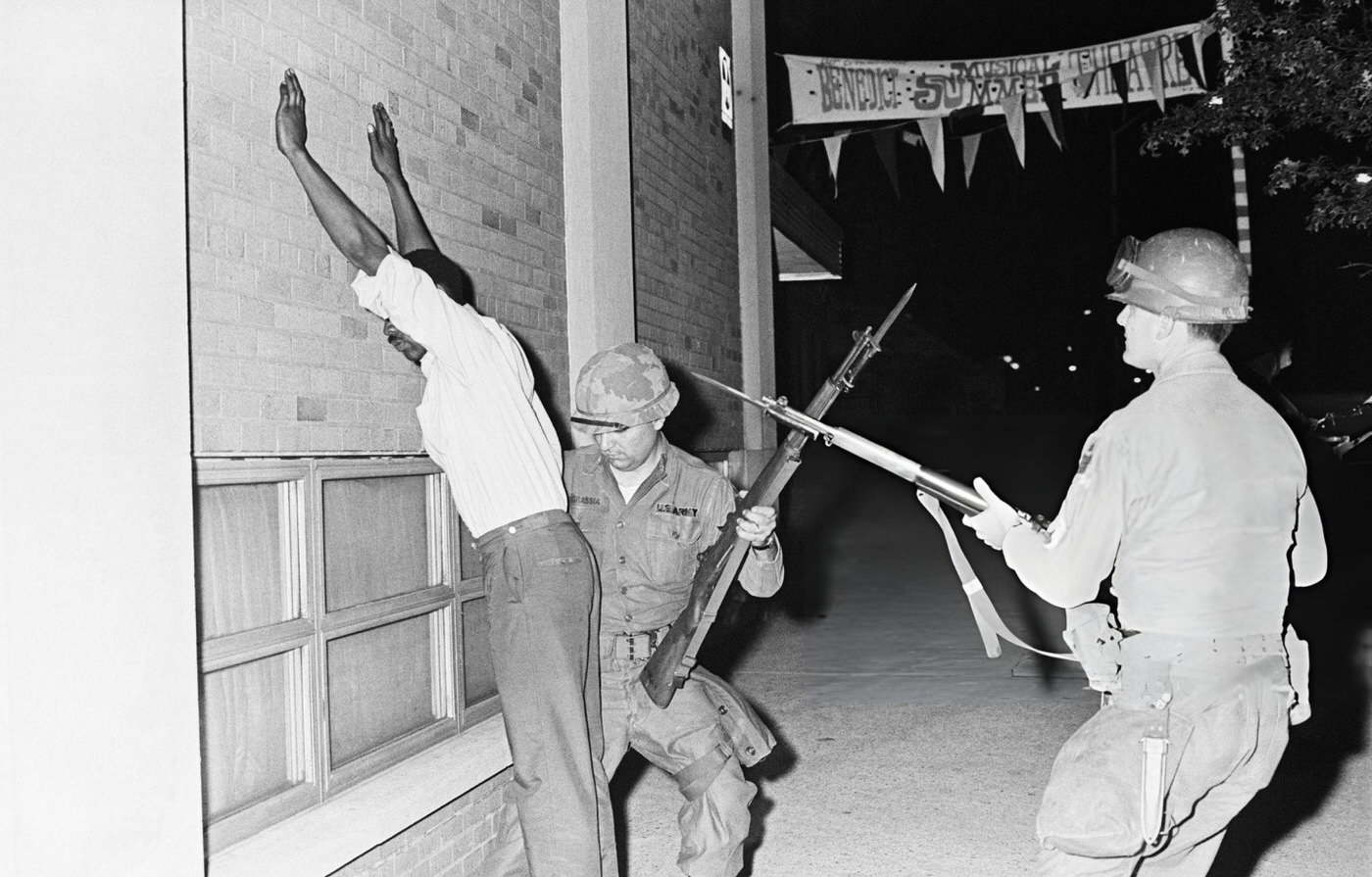 #32 National Guardsmen frisk a suspect at bayonet point during the third consecutive night.