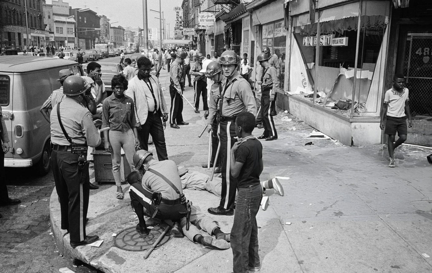 #33 Police officers and National Guardsmen round up looters on a major thoroughfare following a second night of rioting in Newark, New Jersey, 1960s.