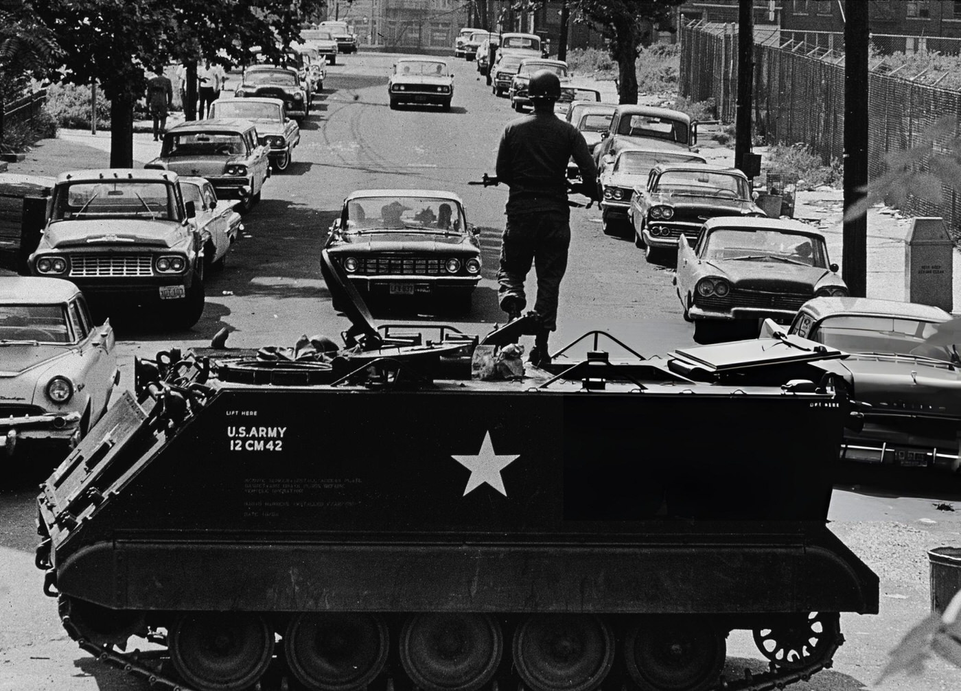 #37 A National Guardsmen stands with a rifle atop a personnel carrier vehicle, blocking traffic leaving the area