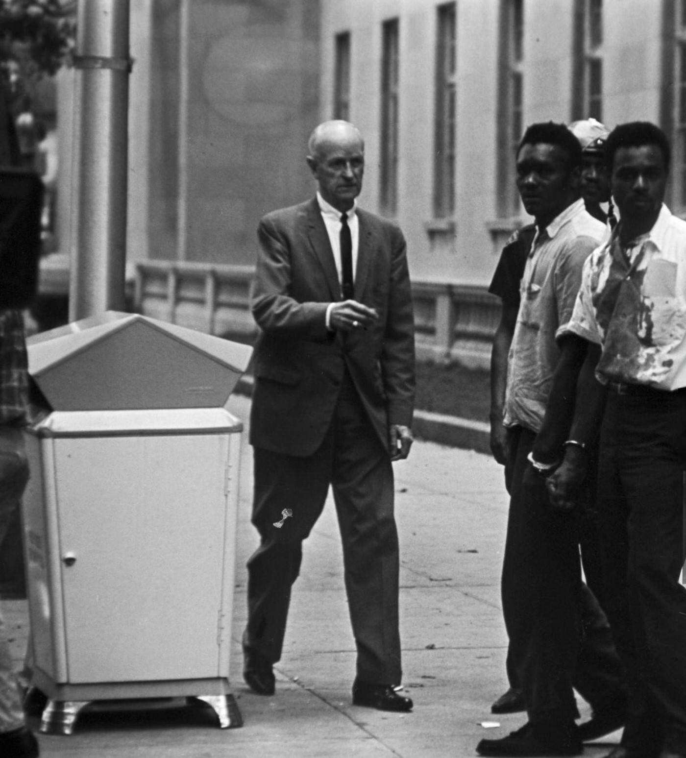 #70 Three young African-American men arrested, chained and handcuffed, one of them wearing a bloodstained white shirt