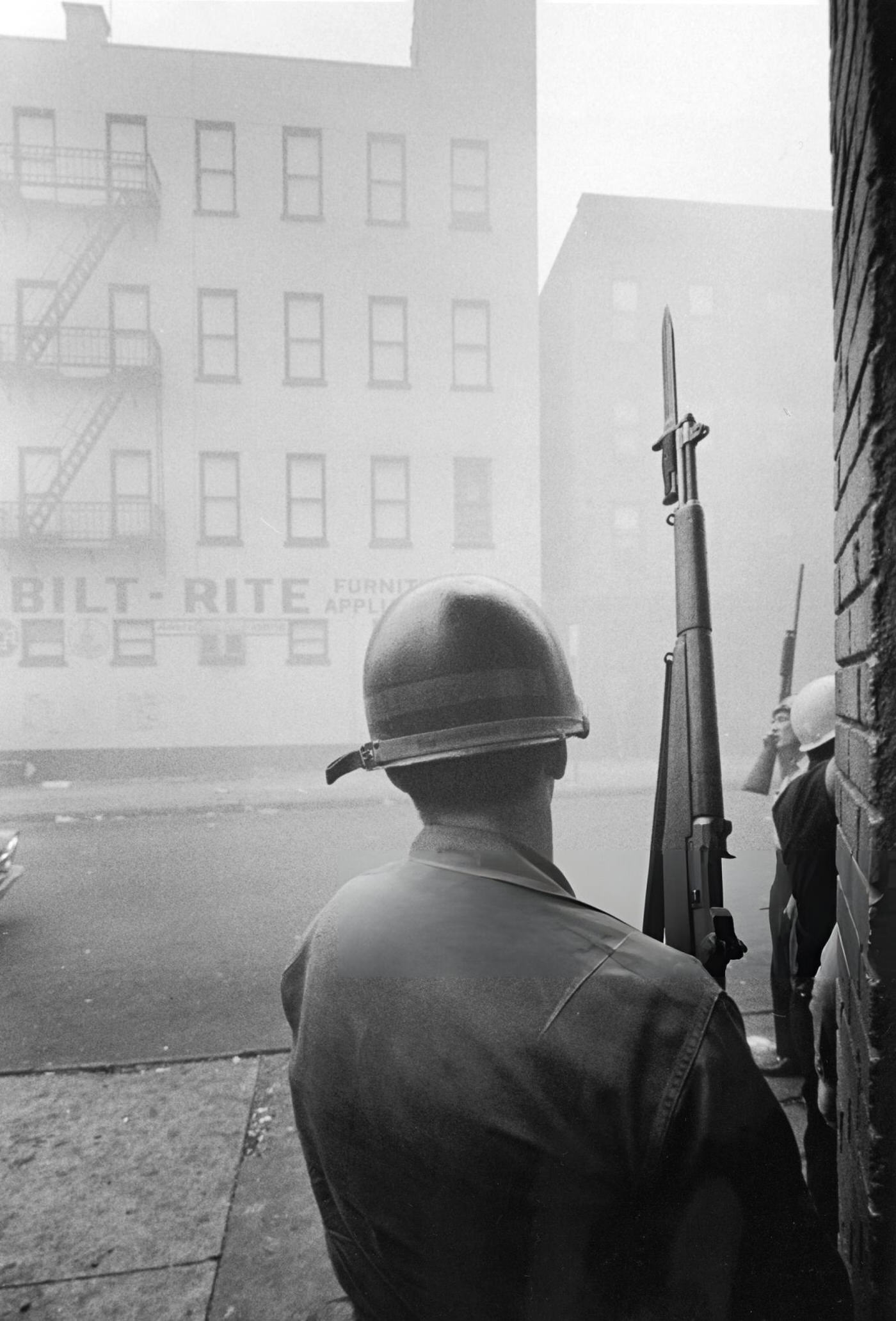 #11 A National Guardsman stands behind a corner and holds a Garand rifle