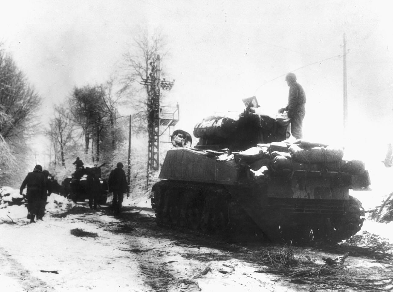 #12 Tanks and infantrymen of the 82nd Airborne Division push through the snow in Belgium, 1944.