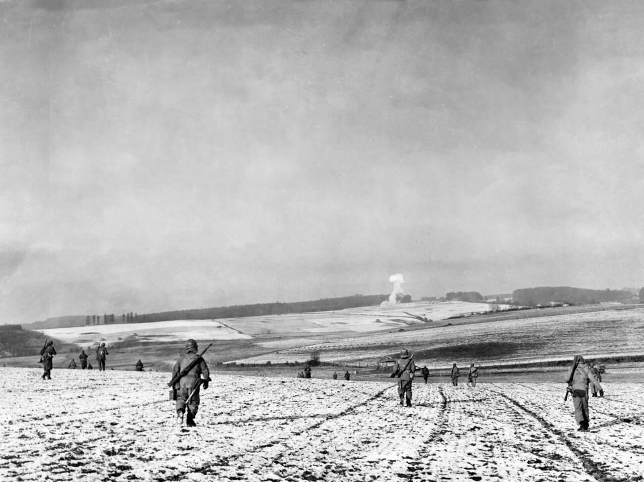 #5 American soldiers advance across fields in the Bastogne area of the Ardennes, Belgium, during the Battle of the Bulge, 1944.