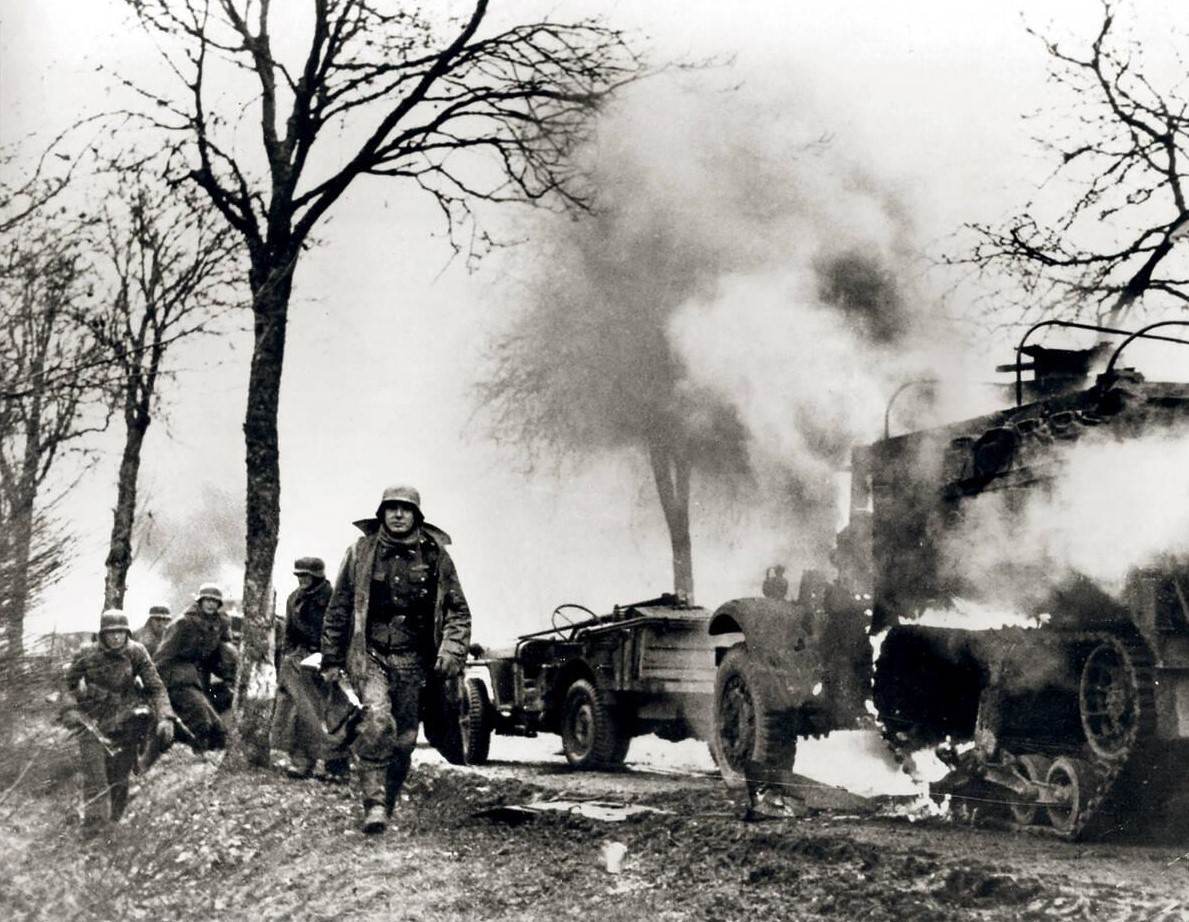 #9 Soldiers from the 2nd SS Panzer Division ‘Das Reich’ walk past a destroyed American convoy in Manhay, Belgium, 1944.