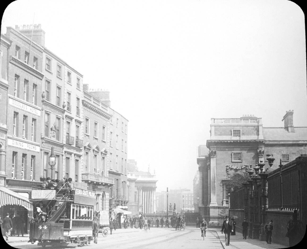 #18 View looking down Grafton Street in Dublin during Victorian times. The Douglas’s Hotel and Dining Rooms are visible on the left, and the number 44 horse drawn tram shows adverts for Zebra Grate Polish.