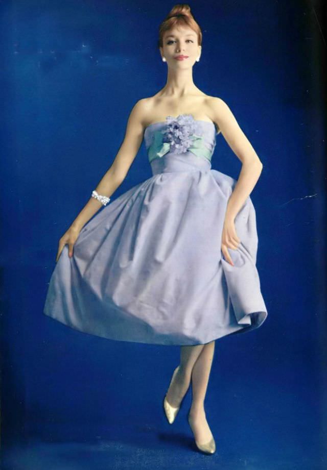 #31 Gunila in a lovely pale lilac velvet dress, the strapless bodice is wrapped in pale green faille ribbon with a corsage of violets, by Pierre Balmain, 1958.