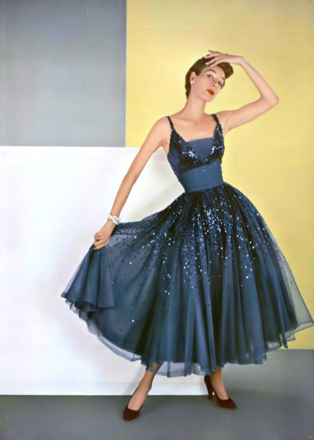 #7 A model in a midnight blue chiffon dance dress strewn with sparkling sequins by Pierre Balmain, 1953.